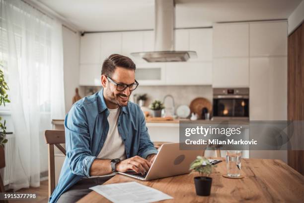 a young man works from home using a laptop - portrait of pensive young businessman wearing glasses stock pictures, royalty-free photos & images