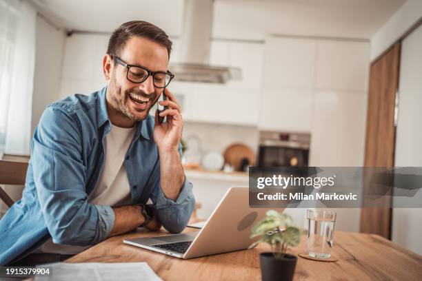 a young man works from home using a laptop - portrait of pensive young businessman wearing glasses stock-fotos und bilder