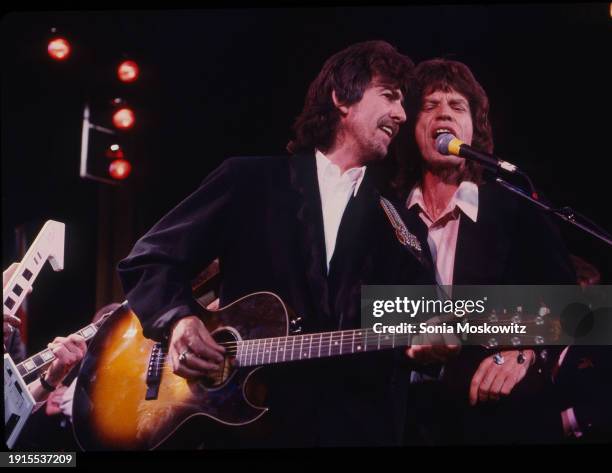 View of musician George Harrison , on guitar, and singer Mick Jagger as they perform during the Rock and Roll Hall of Fame Awards ceremony at the...