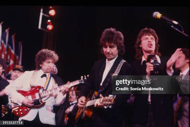 View of, from left, musicians Bob Dylan & George Harrison, both on guitar, and singer Mick Jagger as they perform during the Rock and Roll Hall of...