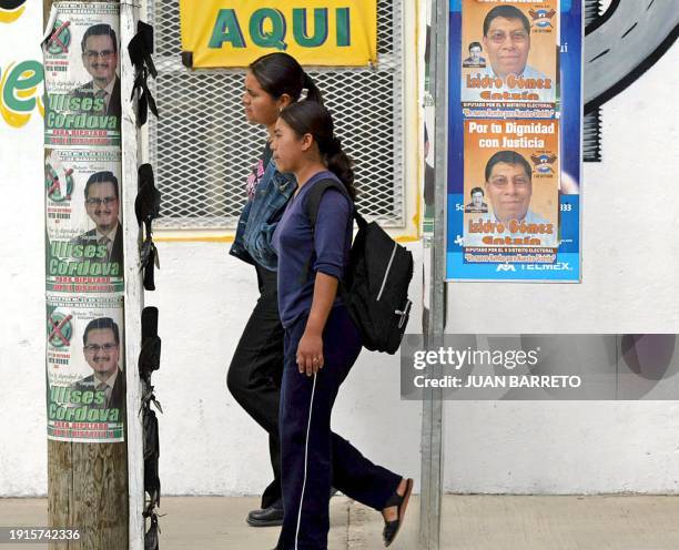 Mujeres pasan junto a carteles de candidatos municipales en San Cristóbal, al sureste de Ciudad de México el 02 de octubre de 2004. El estado...