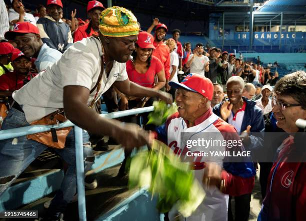 Fan cleans with herbs Cuban former baseball player Tony Oliva, member of they MLB Hall of Fame, before the match between Artemisa Industriales at the...
