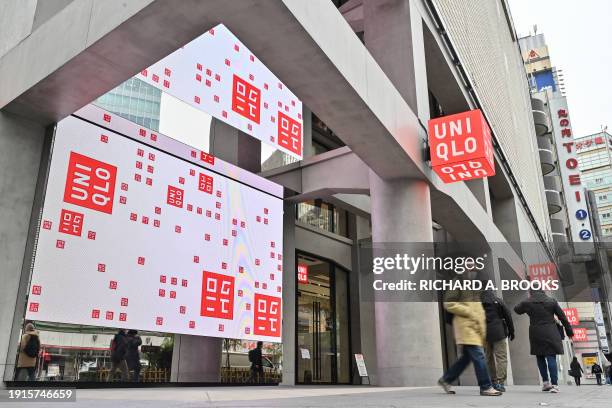Pedestrians walk past a branch of the Fast Retailing clothing brand Uniqlo along a street in Tokyo on January 11, 2024. Fast Retailing were expected...