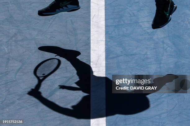 France's Adrian Mannarino casts a shadow as he serves during a practice session on Rod Laver Arena in Melbourne on January 11, 2024 ahead of the...