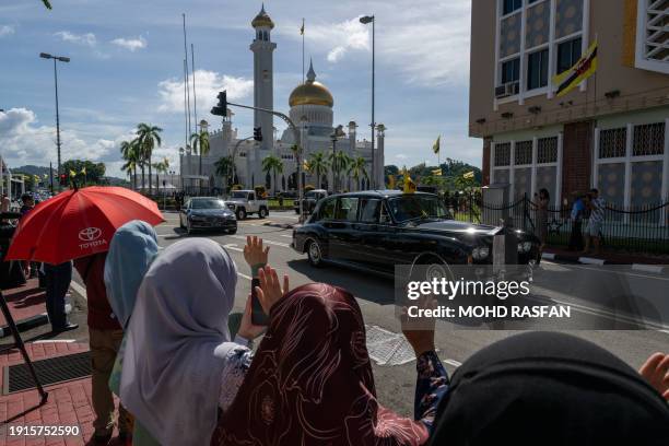 People wave to a car carrying Brunei's Sultan Hassanal Bolkiah after his son Prince Abdul Mateen's solemnization as part of the royal wedding at...