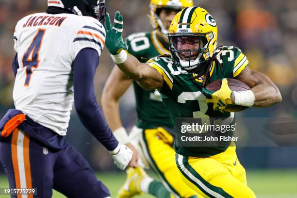 Aaron Jones of the Green Bay Packers stiff arms Eddie Jackson of the Chicago Bears during the fourth quarter at Lambeau Field on January 07, 2024 in...