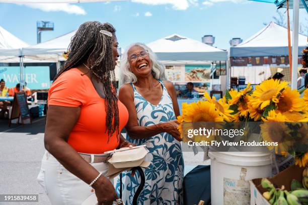 guía turístico local hawaiano y cliente mayor mirando flores juntos en el mercado de agricultores - florida estados unidos fotografías e imágenes de stock