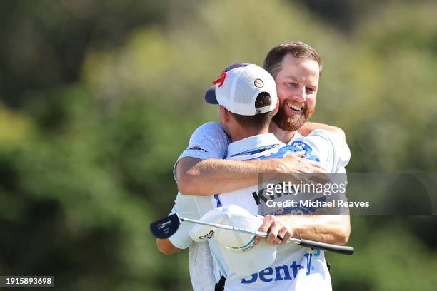 Chris Kirk of the United States celebrates with caddie Michael Cromie after winning on the 18th green during the final round of The Sentry at...