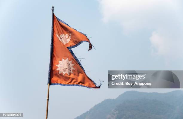the national flag of nepal against sky. the flag of nepal is the only national flag in the world that is not rectangular. - nepal flag stock pictures, royalty-free photos & images