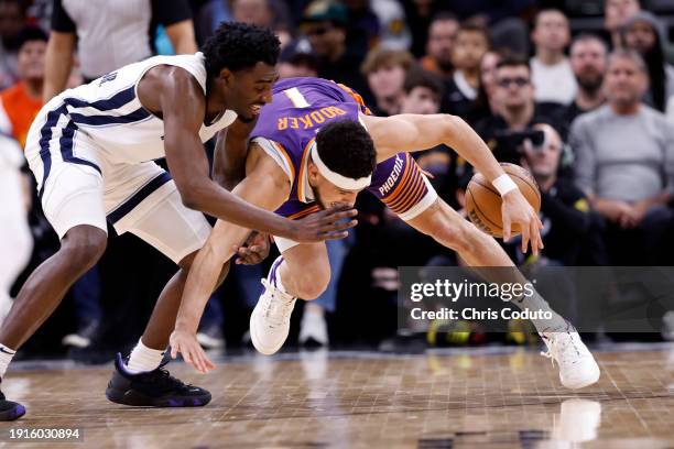 Vince Williams Jr. #5 of the Memphis Grizzlies and Devin Booker of the Phoenix Suns battle for control of a loose ball during the first half at...