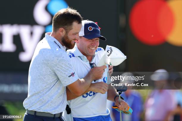 Chris Kirk of the United States celebrates with caddie Michael Cromie after winning on the 18th green during the final round of The Sentry at...