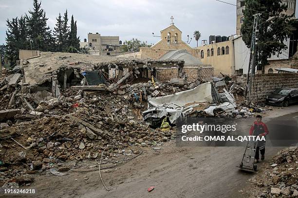 Young boy walks in front of Gaza City's Greek Orthodox Church of Saint Porphyrius on January 5 damaged in Israeli bombardment during the ongoing...