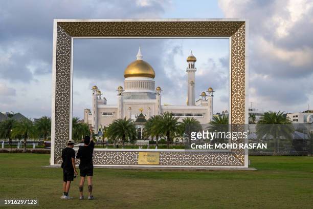 Tourists from Thailand take pictures of the Sultan Omar Ali Saifuddien Mosque in Bandar Seri Begawan on January 11, 2024.