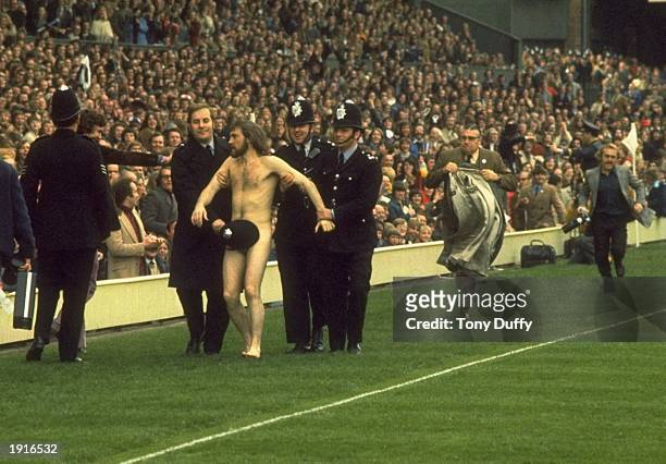 Police Constable Michael O’Brien uses his helmet to cover up streaker Bruce Perry as he is led away during the Five Nations Championship match...