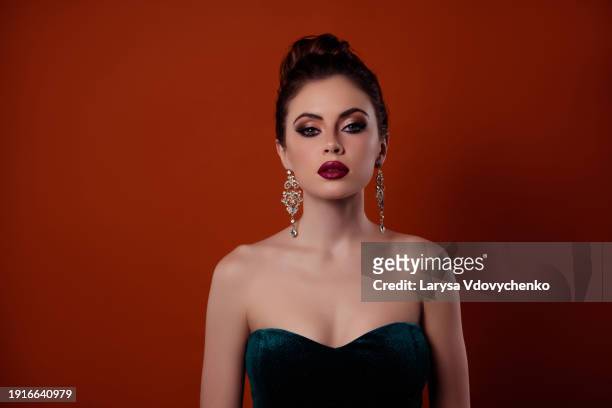 photo of young fatale femme model with bright lips pomade wearing expensive diamonds isolated on red color background - femme glamour stock pictures, royalty-free photos & images