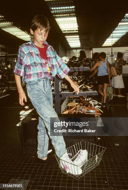 Nineties young man tries on new trainers in a department. Store in central Warsaw, on 16th June 1990, in Warsaw, Poland.