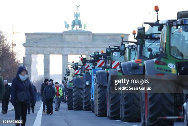 Tractors of protesting farmers line Strasse des 17. Juni street in front of the Brandenburg Gate on the first day of a week of protests on January...