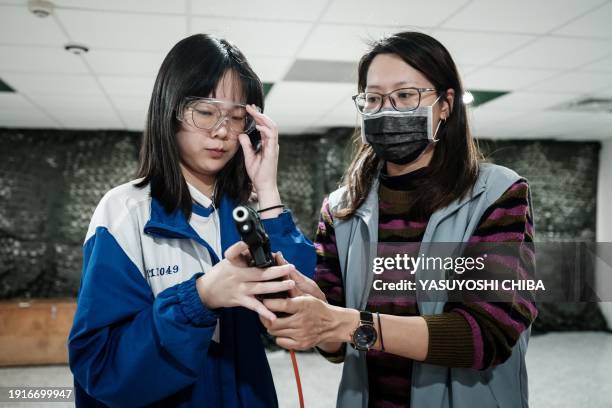 Student learns how to use an airsoft gun from a Taiwanese military instructor at Kaohsiung Municipal Sanmin Senior High School in Kaohsiung on...