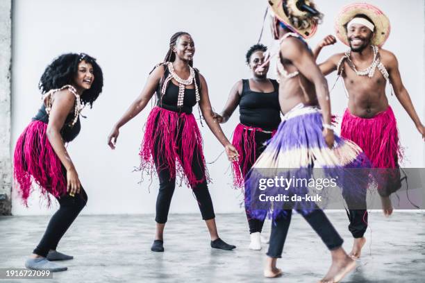 afrikaner in traditionellen kostümen tanzen zusammen und haben spaß - afrikanischer volksstamm stock-fotos und bilder