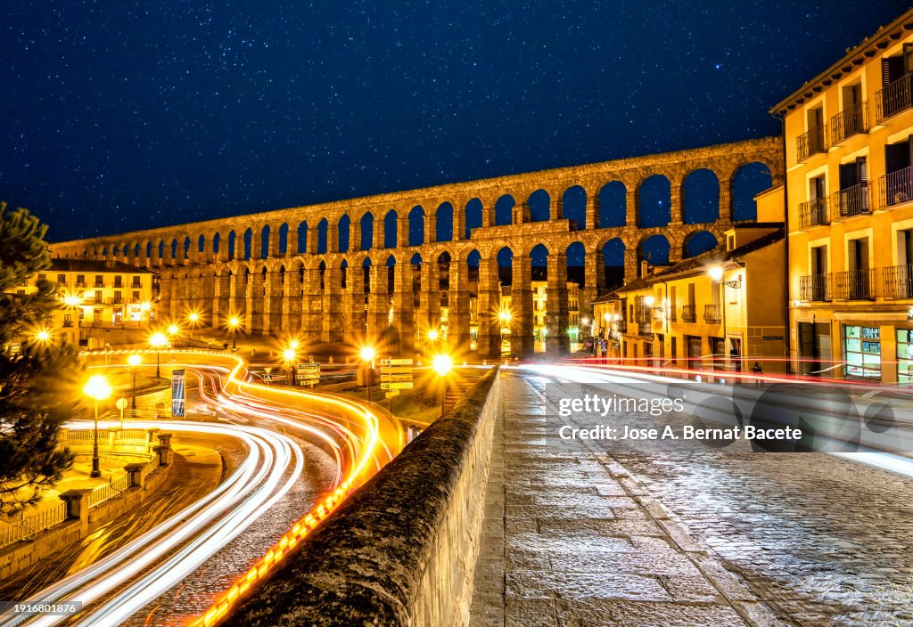 View of the city of Segovia and the Acueducto Romano (Roman aqueduct) to the light of the Moon with the lights and trails of moving cars.