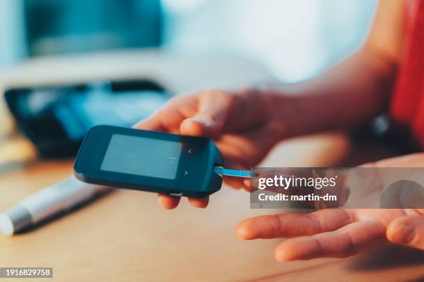 woman with diabetes pricking finger with lancet for daily blood sugar check - blood sugar test stock pictures, royalty-free photos & images