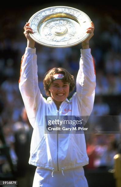 Martina Hingis of Switzerland holds the trophy aloft after her victory in the Women's Singles final against Jana Novotna of the Czech Republic during...