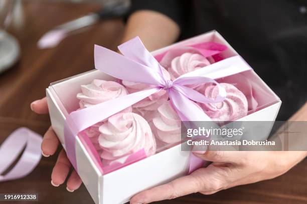close up womans hands tie ribbon on box for customer order. bakery chef baking pastry and cake in the kitchen. small business entrepreneur and food delivery concept. - zephyros stock-fotos und bilder