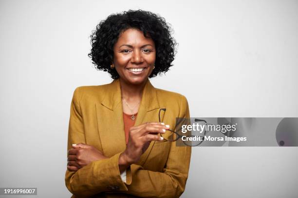 mature female ceo with arms crossed and glasses in hand. - foto ritratto ufficiale foto e immagini stock
