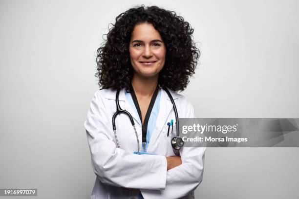 confident female doctor with arms crossed against white background - foto ritratto ufficiale foto e immagini stock