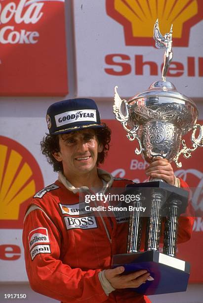 McLaren TAG driver Alain Prost of France holds the trophy as he stands on the winners'' podium after his victory in the Brazilian Grand Prix at the...