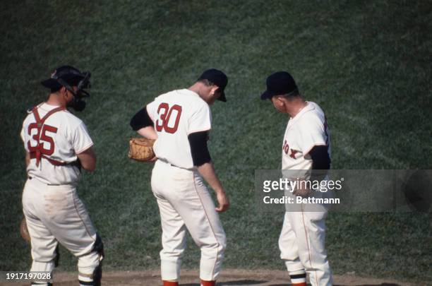 The Boston Red Sox' pitcher Jose Santiago, catcher Russ Gibson and manager Dick Williams confer on the pitching mound during the World Series opening...