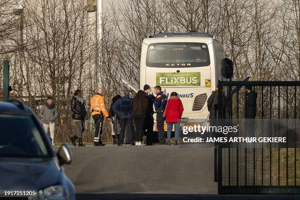 Belgian police and passengers stand outside an intercity travel service bus after it was stopped following a report of a conversation of a possible...
