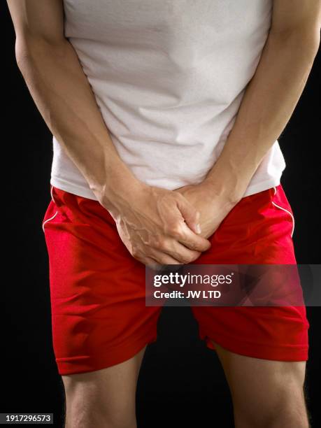 man clutching his crotch - fortpflanzungsorgan stock-fotos und bilder