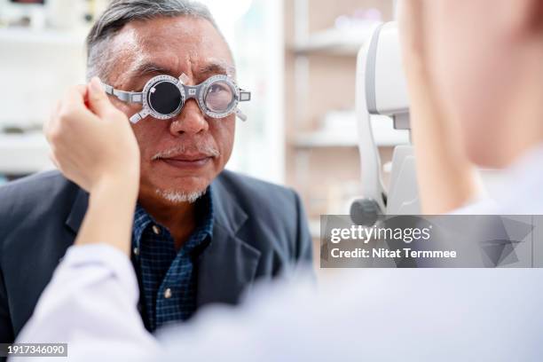 improved eyesight and identifying potential health issues a comprehensive eye exam for old adults. a senior male during eye exam with optometrist by diopter tool an ophthalmology clinic. - catarata fotografías e imágenes de stock