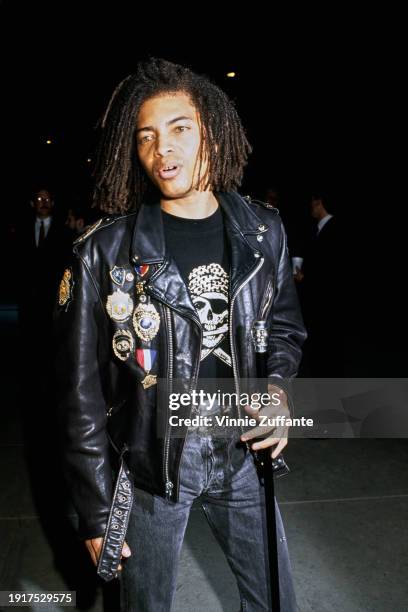 American singer and songwriter Terence Trent D'Arby, wearing a black leather jacket with badges pinned to it over a black t-shirt with a...