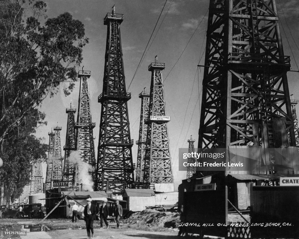 Oil Derricks A low-angle view shows a group of oil field workers dwarfed by... News ...
