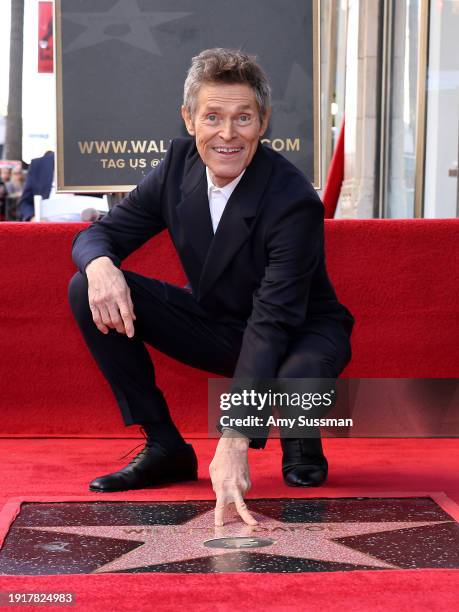 Willem Dafoe poses with his star during his Hollywood Walk of Fame Star Ceremony on January 08, 2024 in Hollywood, California.