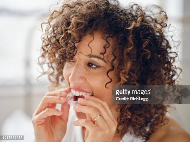 woman in bed in the morning using clear teeth aligners - invisalign stockfoto's en -beelden