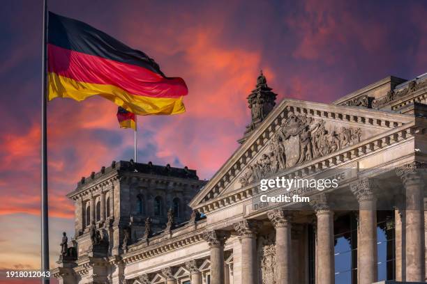deutscher bundestag - reichstag building and german flag at sunset (german parliament building) - berlin, germany - reichstag photos et images de collection