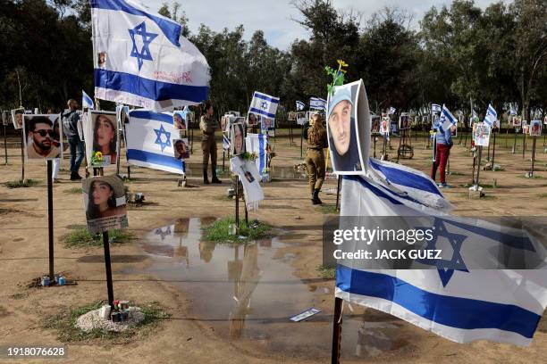 Israeli soldiers walk among portraits of people taken captive or killed by Hamas militants during the Supernova music festival on October 7, during a...