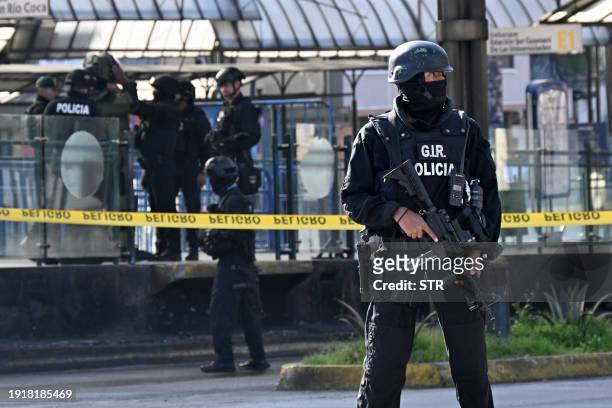 National Police officers stand guard as a member of the bomb squad inspects a suspicious package left at La Marin bus station in Quito, on January 11...