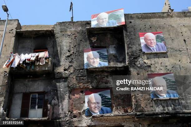 Posters of Lebanese Muslim Sunni candidate for the parliamentary elections, Najib Mikati, are seen hanged on a building still bearing scars of the...