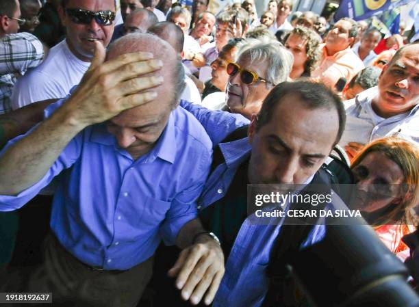 Brazil's presidential candidate Jose Serra of the Social Democratic Party of Brazil protects his head after being "knocked silly" by a thrown object,...