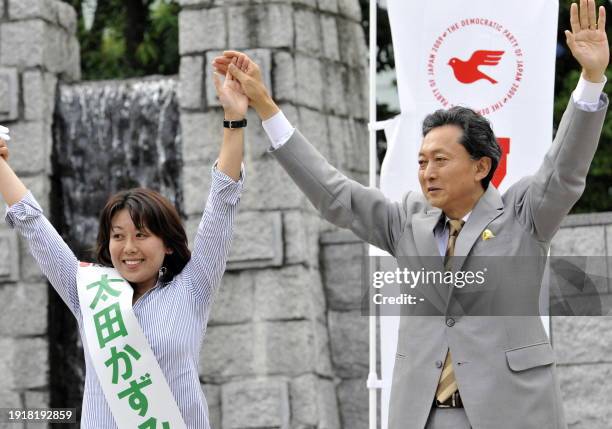 Japan's main opposition Democratic Party of Japan leader Yukio Hatoyama raises hands with his party's young female candidate Kazumi Ota at a rally...