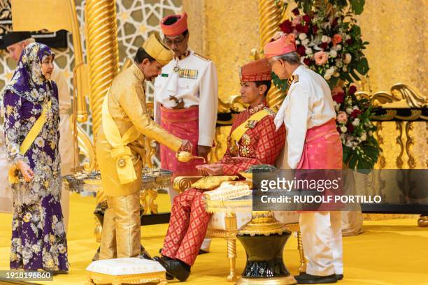 This photograph taken on January 10, 2024 shows Brunei's Sultan Hassanal Bolkiah pouring scented oil on the hands of Prince Abdul Mateen during the...