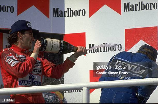 McLaren Honda driver Ayrton Senna of Brazil sprays Williams Renault driver Thierry Boutsen of Belgium as they stand on the winners'' podium after the...