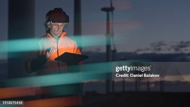 ai and vr use in wind farm. engineer works with vr glasses and hud holographic. night shift. - digitization stockfoto's en -beelden