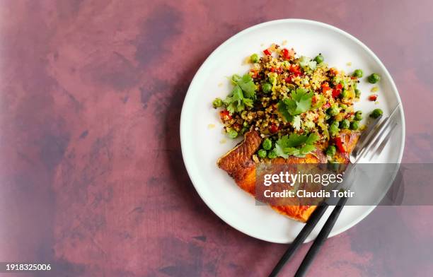 plate of baked salmon and quinoa salad on red background - red bell pepper stock pictures, royalty-free photos & images