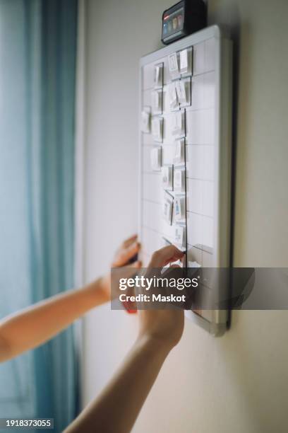 hands of boy preparing to do list mounted on wall at home - add list stock pictures, royalty-free photos & images