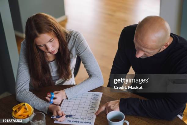 high angle view of father and daughter preparing school list while sitting at home - add list stock pictures, royalty-free photos & images